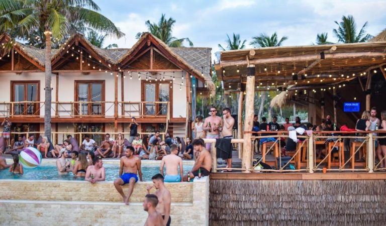 Guests relaxing by the pool and enjoying the lively social atmosphere at Mad Monkey Gili Trawangan hostel.