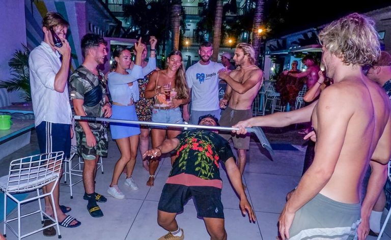 Guests taking part in a limbo contest during a lively party night at Mad Monkey Kuta Lombok Hostel.