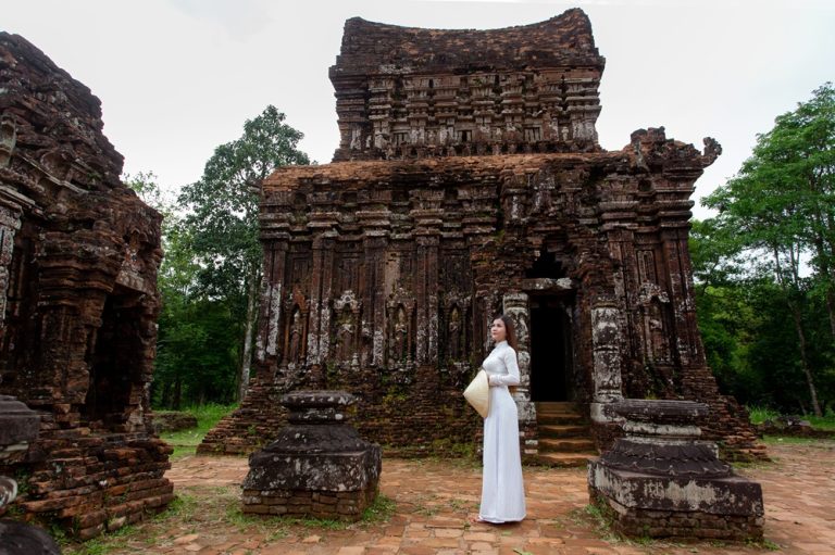 Ancient Cham temple at My Son Sanctuary in central Vietnam with a visitor wearing a traditional áo dài