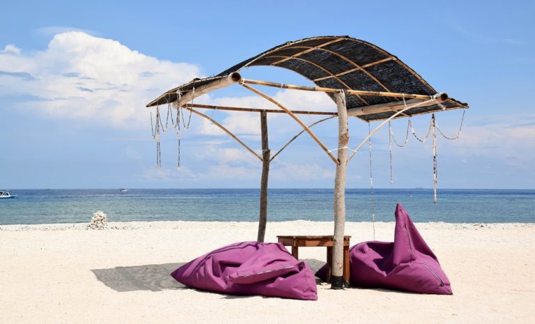 Beachfront seating with beanbags and ocean views on one of the Gili Islands, perfect for relaxing by the sea. Caption Description