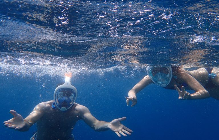 Travelers snorkeling in the crystal-clear waters surrounding the Gili Islands, exploring vibrant coral reefs and tropical marine life. Caption Description