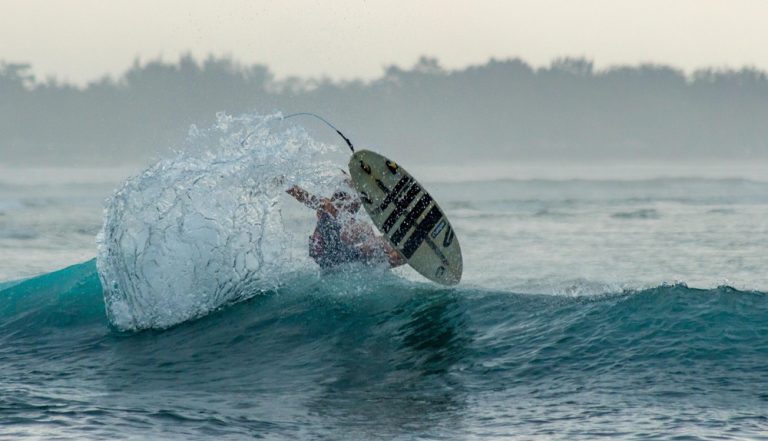 Surfer performing a powerful cutback on a wave in Bali, featured in this Bali surf guide. Caption Description