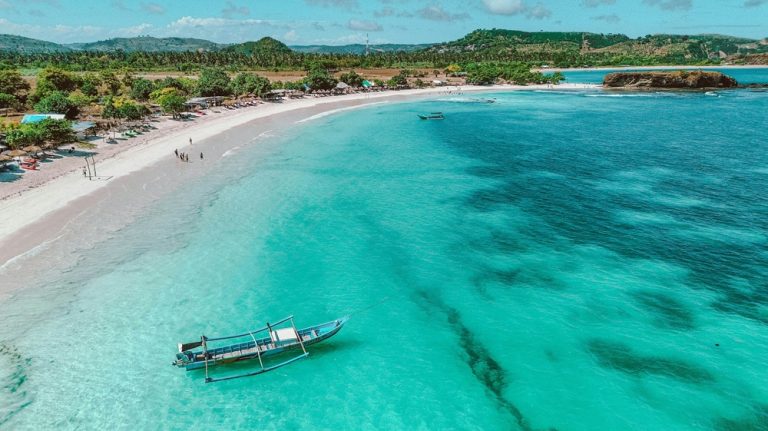 Aerial view of Tanjung Aan Beach with turquoise water, white sand and a traditional boat near Kuta Lombok, Lombok, Indonesia. Caption Description