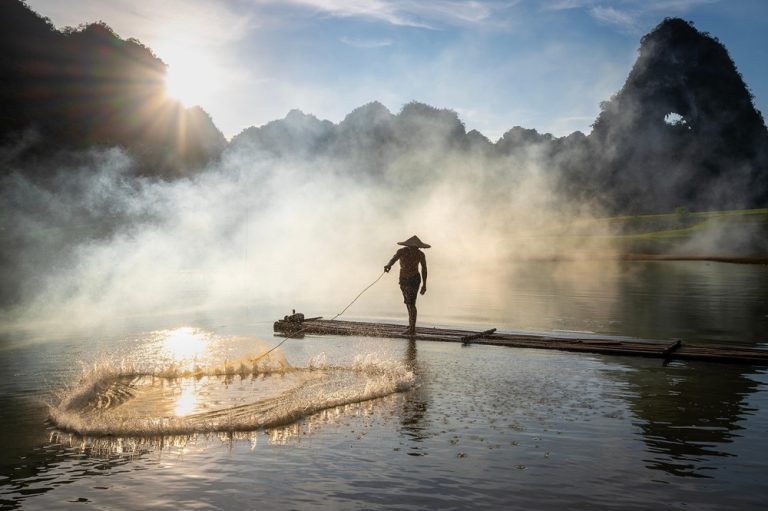 Traditional fisherman on a bamboo raft in Ninh Binh, one of the best things to do in Vietnam Caption Description