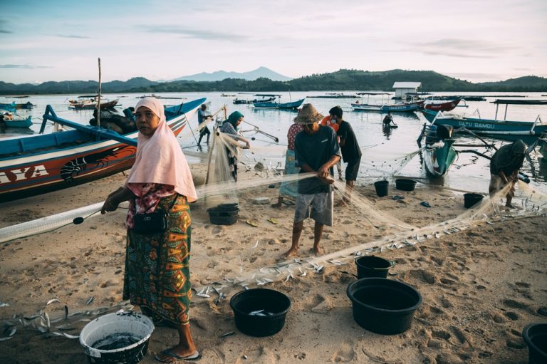 Local fishermen preparing their nets on a beach near Kuta Lombok, showcasing traditional coastal life in Lombok, Indonesia. Caption Description