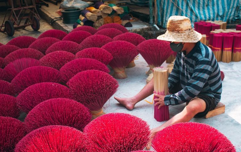 Craftsman bundling bright red incense sticks at a traditional incense village in southern Vietnam