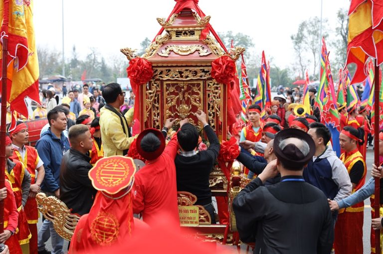 Traditional Vietnamese festival procession with ornate ceremonial palanquin, colourful flags and participants in traditional dress Caption Description