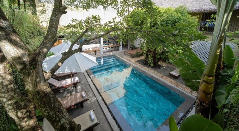 Swimming pool at 9Station Hostel & Bar Phu Quoc surrounded by tropical gardens, offering a relaxing social atmosphere for travellers on Phu Quoc Island.