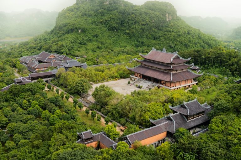 Aerial view of Bai Dinh Pagoda surrounded by forested limestone mountains in Ninh Binh