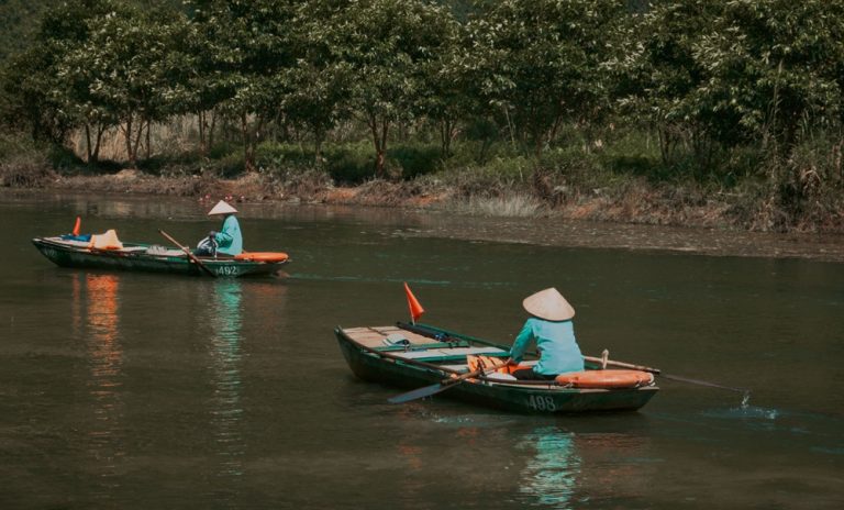 Traditional rowboats in Tam Coc, Ninh Binh, one of the most peaceful places to visit in Vietnam Caption Description