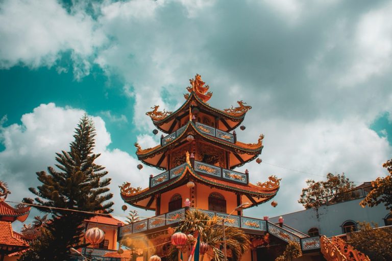Traditional Buddhist pagoda with ornate architecture under dramatic skies in Vietnam Caption Description