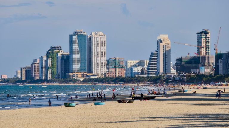Sandy beach in Da Nang with swimmers, traditional basket boats and beachfront hotels