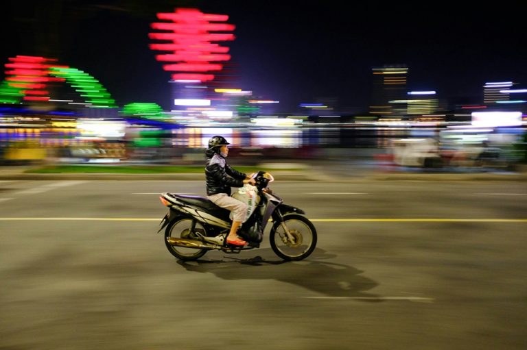 Motorbike rider traveling through Da Nang at night in Central Vietnam