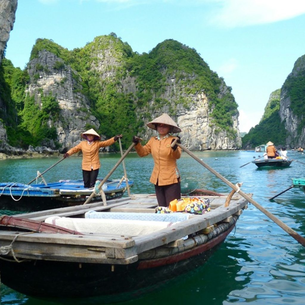 Traditional boats surrounded by limestone karsts in Ha Long Bay for a Vietnam packing list travel guide.