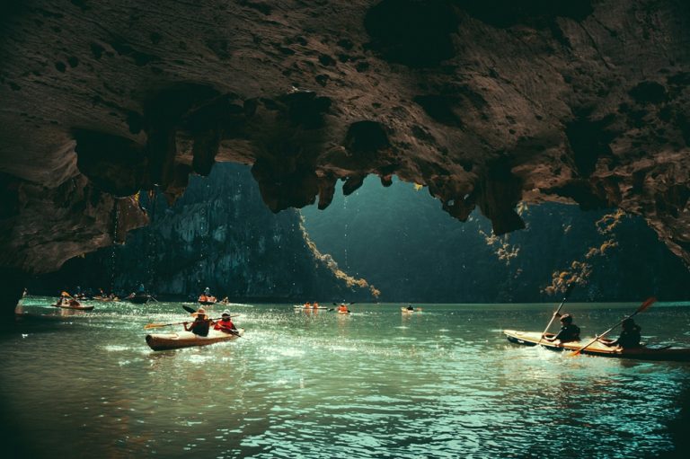 Kayakers exploring a limestone cave in Ha Long Bay during the best time to visit Vietnam