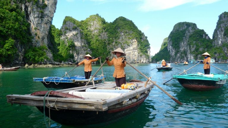Traditional wooden boats navigating the emerald waters of Ha Long Bay surrounded by towering limestone karsts