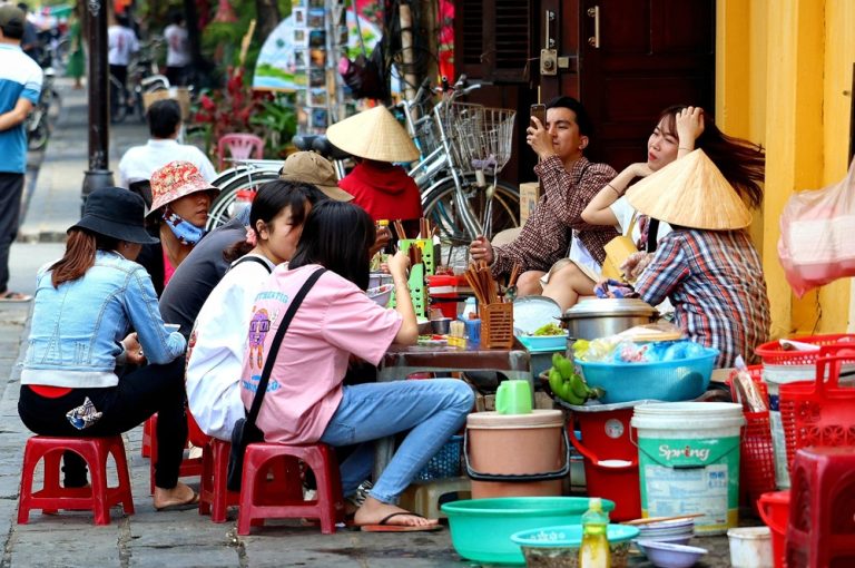 Locals eating at a busy street food stall on the streets of Hanoi