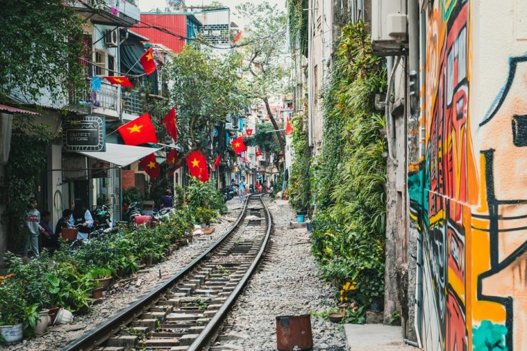The famous Hanoi Train Street lined with cafés, colourful buildings and Vietnamese flags