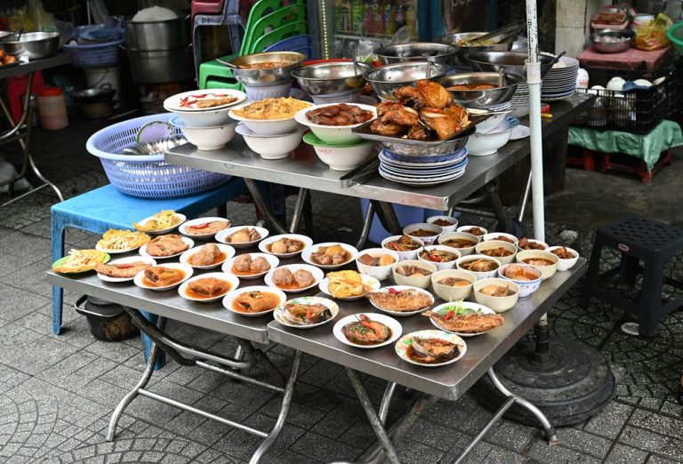 Vietnamese street food stall displaying prepared meat, fish, eggs and local dishes in Ho Chi Minh City
