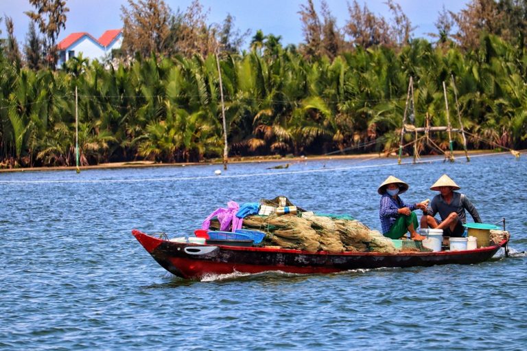 Local fishermen travelling by boat through the waterways of the Hoi An countryside.
