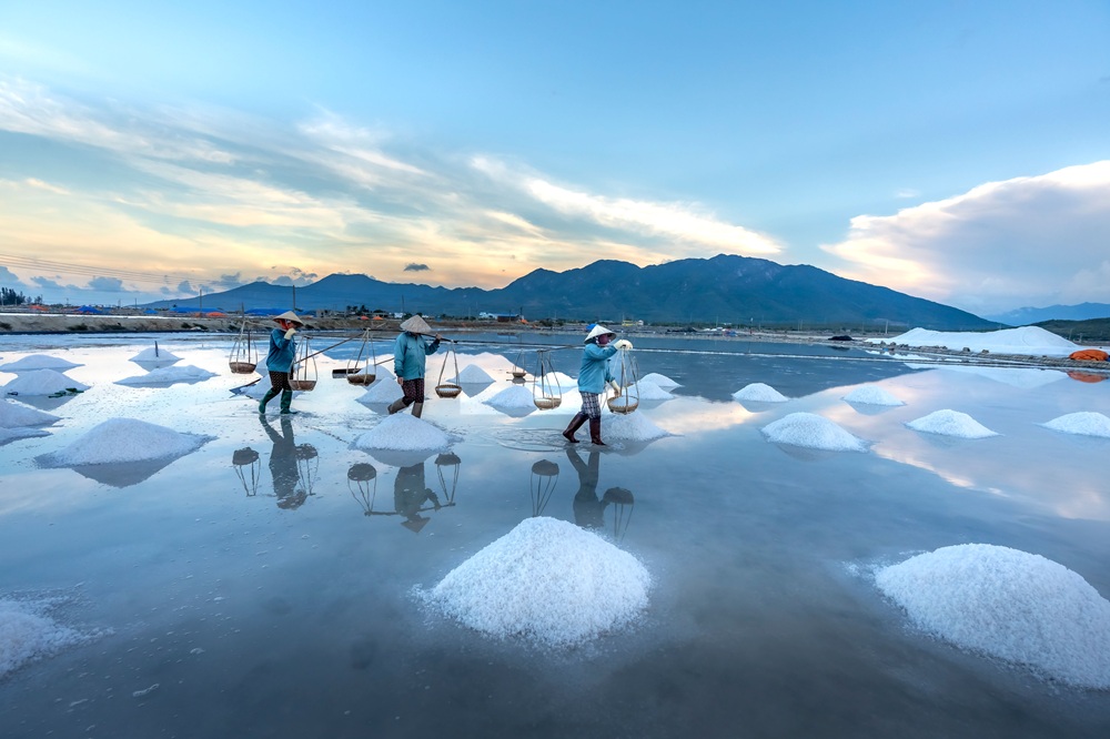 Salt workers harvesting sea salt at Hon Khoi Salt Fields, one of the unique places to visit in Vietnam