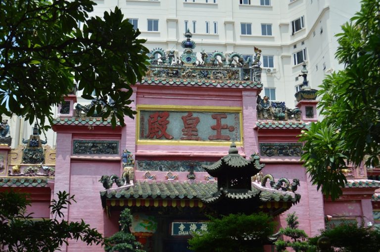 Ornate pink exterior of the Jade Emperor Pagoda surrounded by trees in Ho Chi Minh City