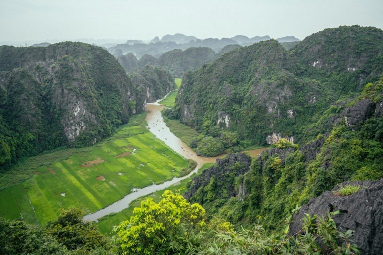 Panoramic view over a winding river, rice fields and limestone karst mountains in Ninh Binh Caption: Description: