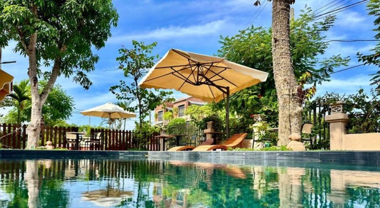 Outdoor swimming pool at Laa House Hoi An surrounded by tropical gardens near Hoi An Ancient Town
