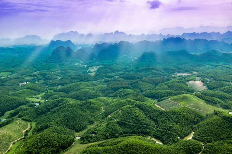 Aerial view across the vast green countryside and limestone karst mountains of Ninh Binh