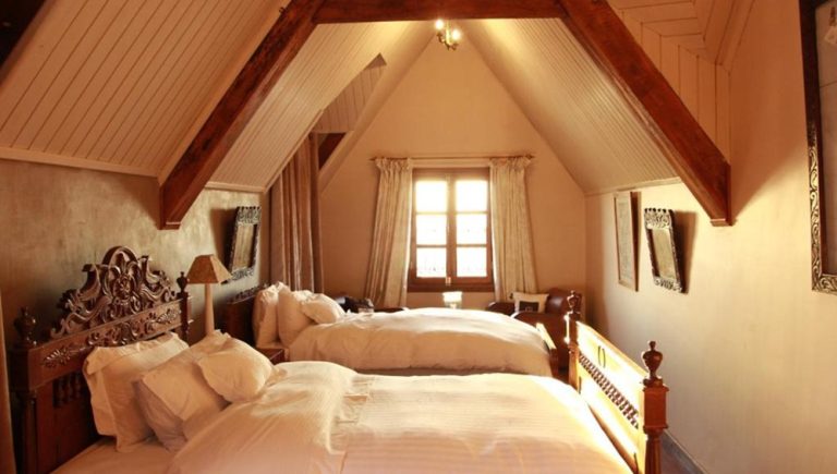 Twin bedroom with traditional wooden furniture at Lokanga Boutique Hotel in Antananarivo, Madagascar