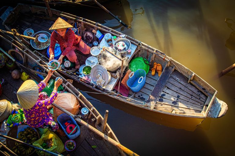 Vendors serving food from traditional boats at a floating market during the best time to visit Vietnam