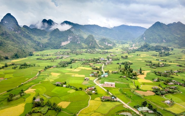 Panoramic view of northern Vietnam's rice fields surrounded by limestone mountains and lush valleys Caption Description