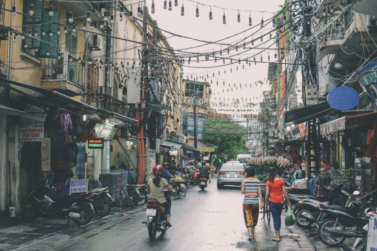 Busy street in Hanoi's Old Quarter with motorbikes, shops and overhead power lines