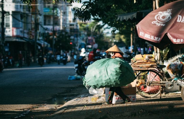 Person carrying a large sack of recyclable materials along a street in Vietnam