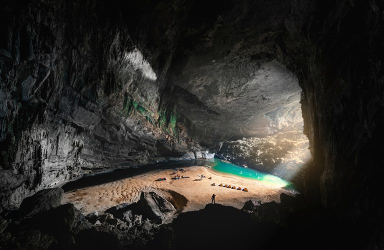 Inside Son Doong Cave with its विशाल underground chamber, sandy floor and emerald river in Phong Nha-Ke Bang National Park, Vietnam Caption Description