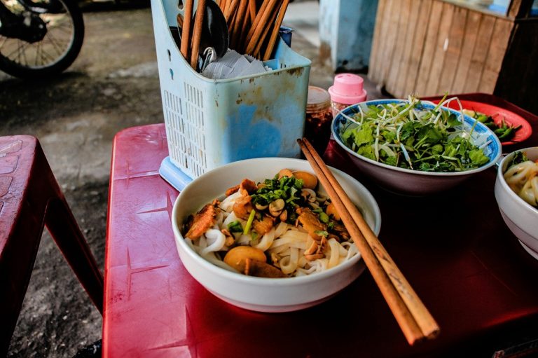 Bowl of Vietnamese noodles with meat, peanuts and fresh herbs at a street food stall in Da Nang