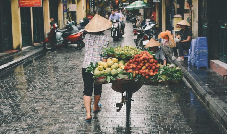 Vietnam Itinerary: Traditional fruit vendor pushing a bicycle through the streets of Hanoi, Vietnam