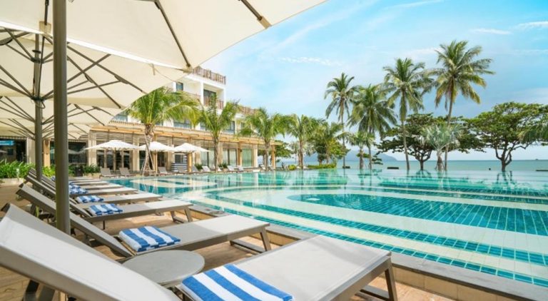 Infinity pool at The Secret Con Dao overlooking the beach and the sea, surrounded by palm trees and sun loungers.