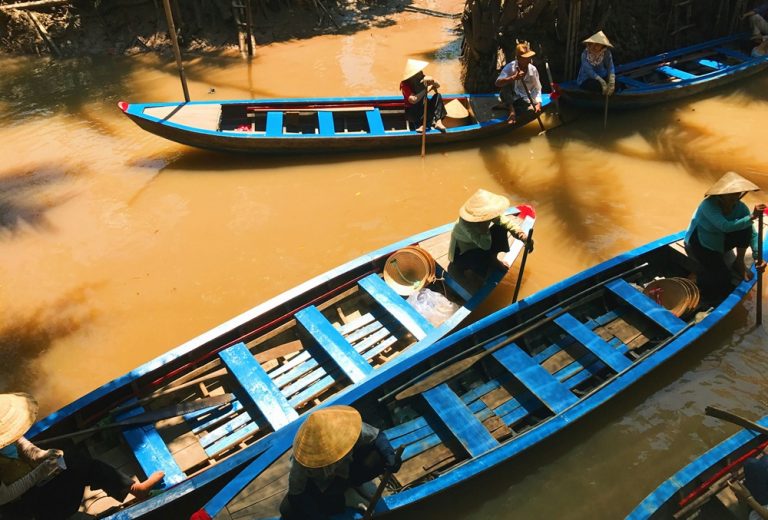 Traditional wooden boats navigating the waterways of the Mekong Delta, showcasing authentic Vietnam travel tips for exploring southern Vietnam.