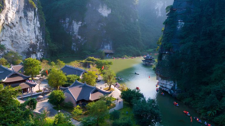 Rowing boats passing temples and towering limestone cliffs at Trang An in Ninh Binh