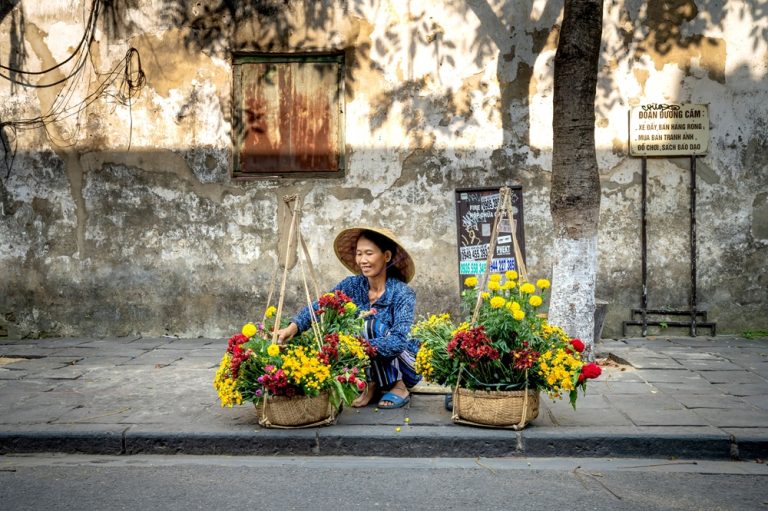 Street flower vendor selling colourful bouquets along a pavement in Hanoi Vietnam