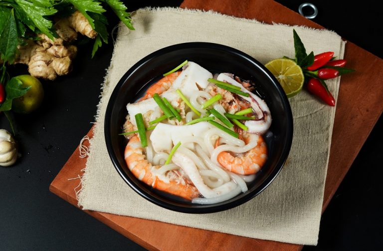 Traditional Vietnamese seafood soup with prawns, squid and fresh herbs, showcasing authentic Vietnamese cuisine and local dining experiences.