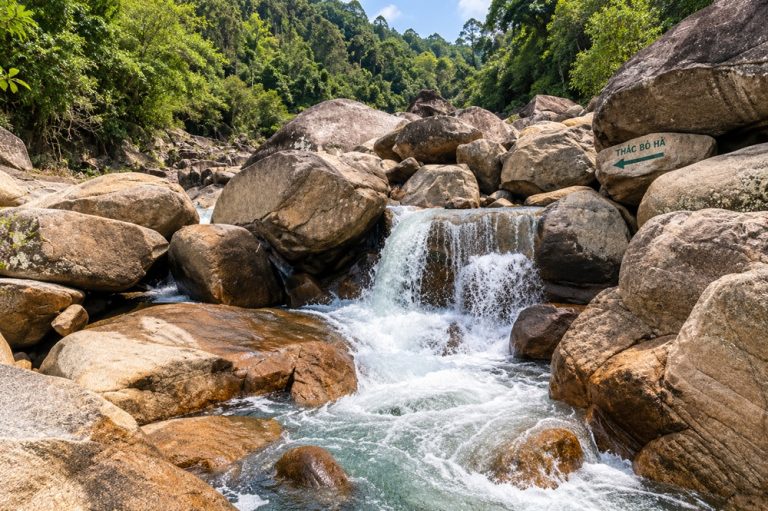 Ba Ho Waterfalls near Nha Trang with clear water cascading between large granite boulders surrounded by tropical forest
