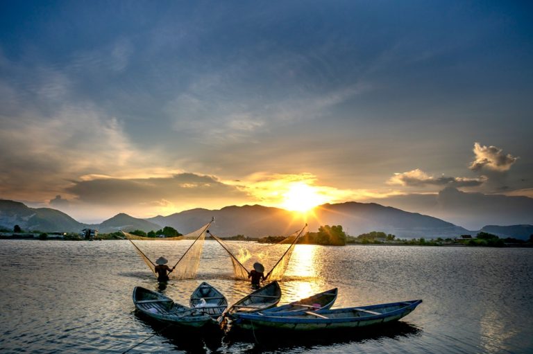 Local fishermen casting traditional nets from the water at sunset near Nha Trang, Vietnam