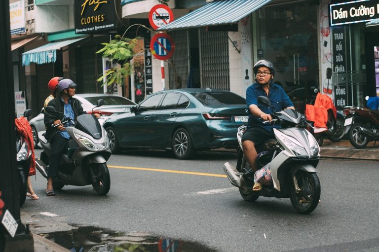 Scooter riders and cars travelling through a busy street in central Nha Trang, Vietnam