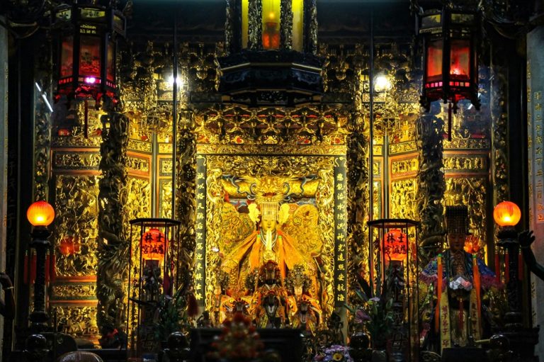 Ornate Mazu shrine with golden carvings, lanterns and religious statues inside a Tainan temple