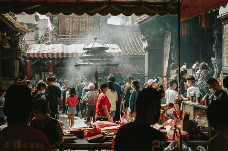 Worshippers gathering around an incense burner inside a traditional temple in Tainan